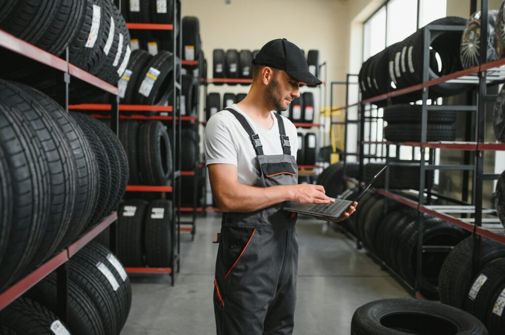 mechanic in blue uniform standing at stock tyre