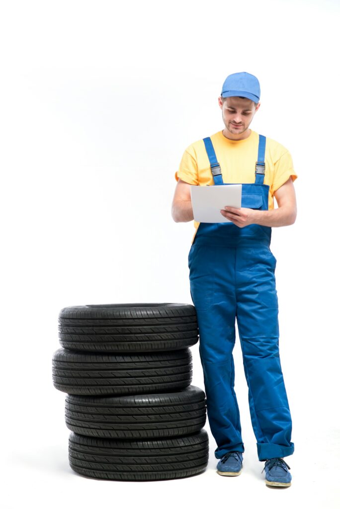 Service worker with notebook against pile of tires