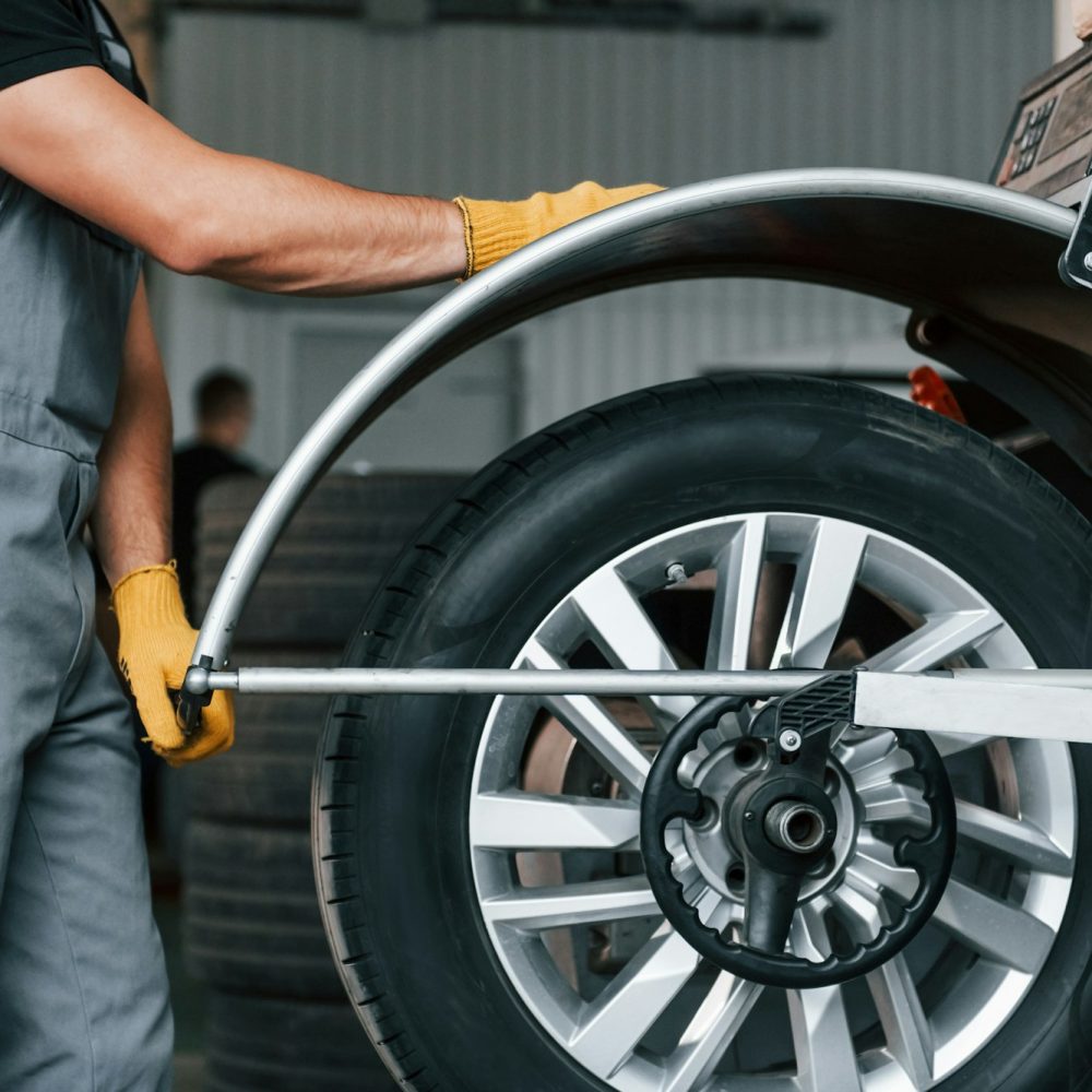 Fixing the tire. Man in uniform is working in the auto service