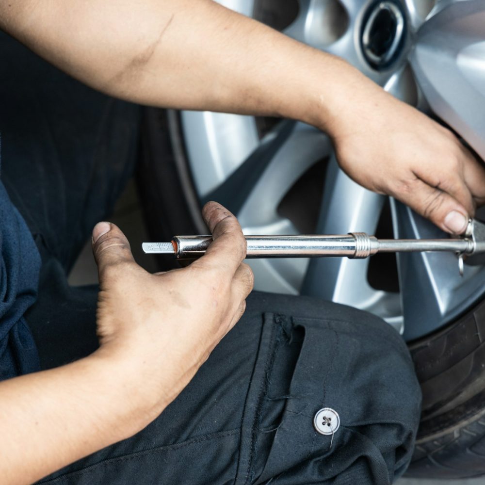 Mechanic checking tire pressure with tyre pressure gauge